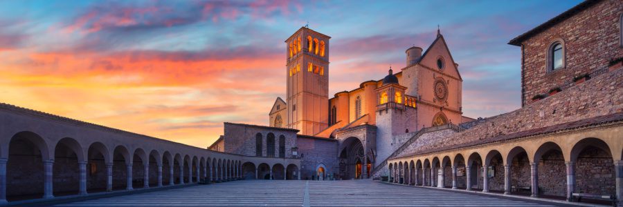 The lower piazza of the Basilica of Saint Francis of Assisi at dusk with colourful sunset sky