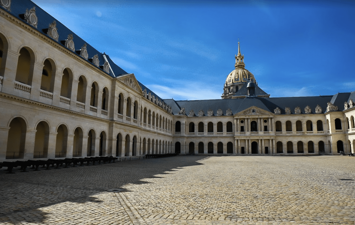 A large gravel courtyard surrounded by a grety building