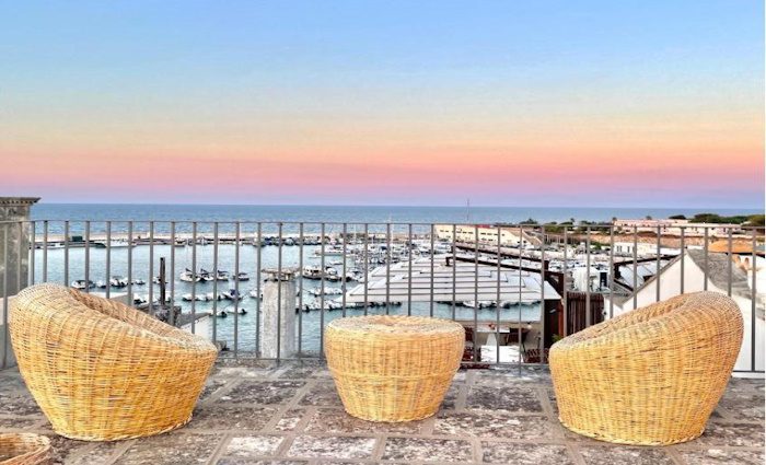 a view from the terrace with wicker chairs overlooking the port