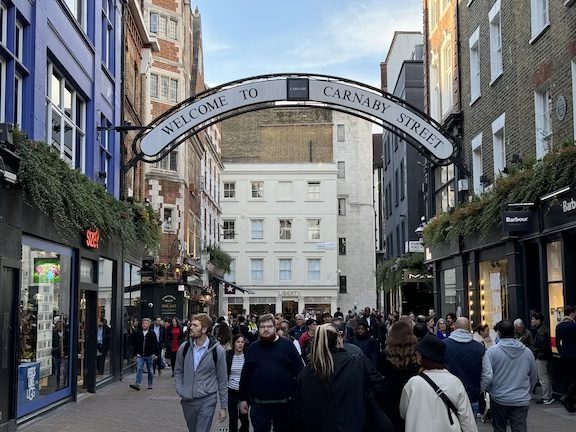 People walking beneath the Carnaby Street sign.