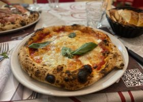 Pizza on a plate topped with a basil leaf.