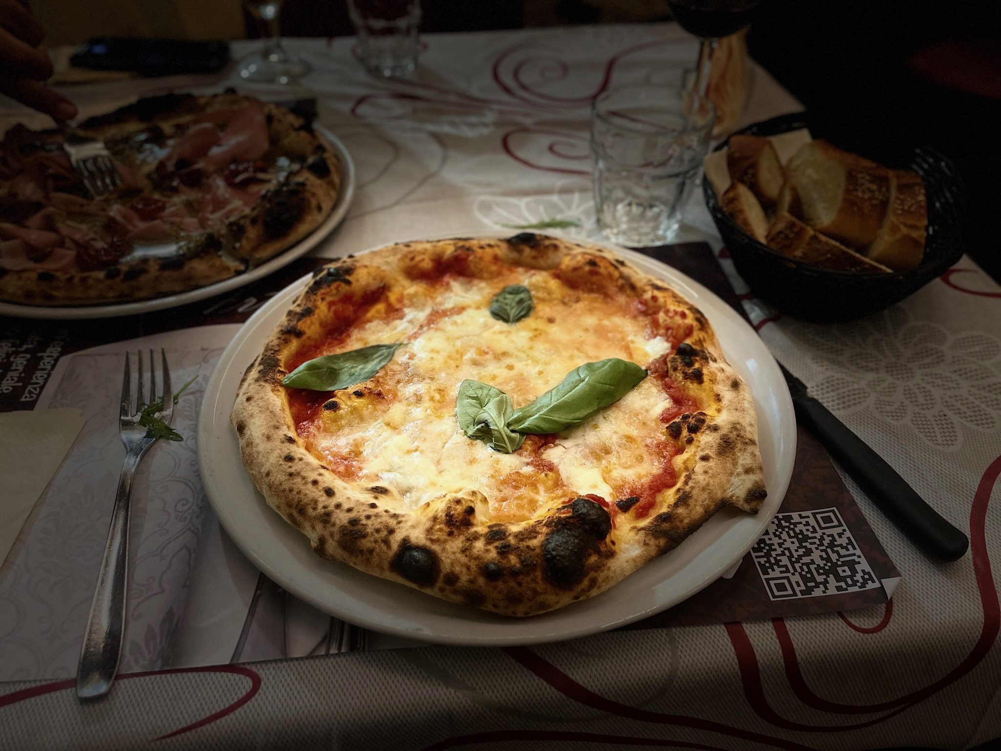 Pizza on a plate topped with basil leaves.