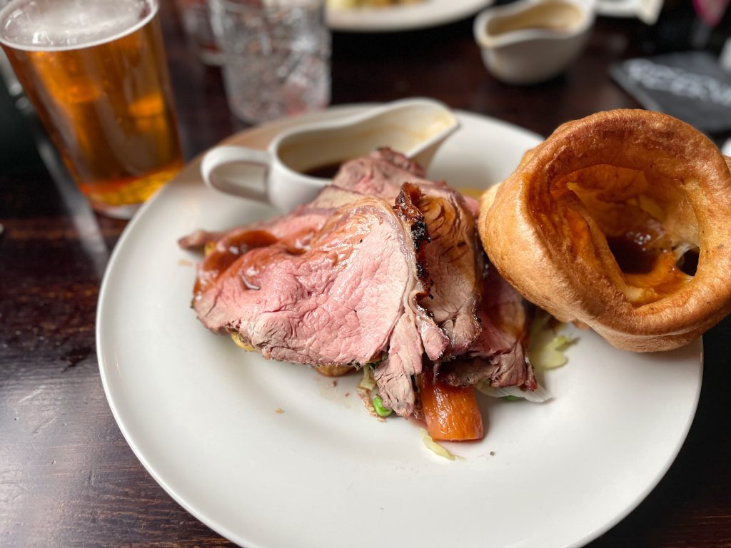 A plate of meat and biscuit with a pint of beer.