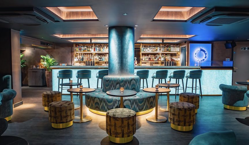 Blue light illuminating a bar and bar stools.