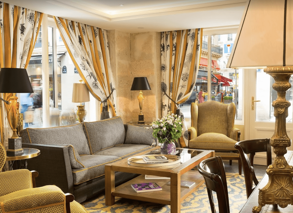 Black, white and yellow floral curtains hang on the windows with a grey couch.