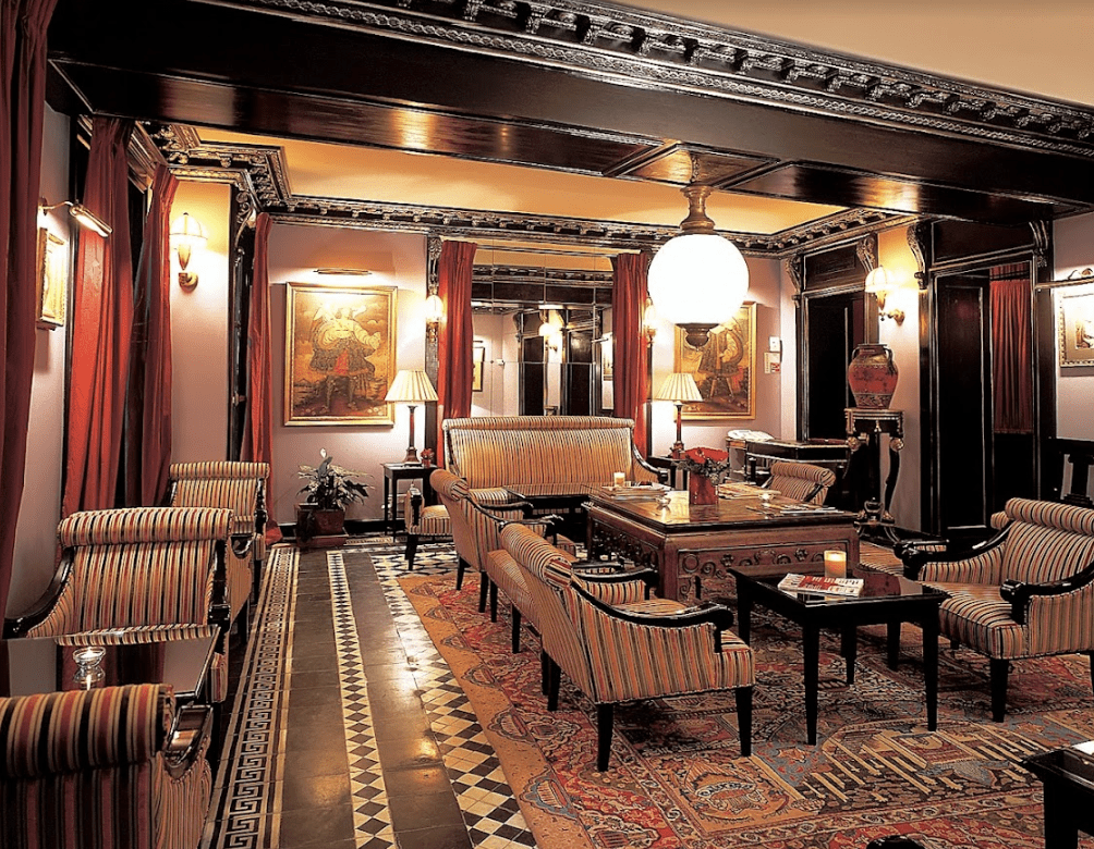 Dark wooden antique beams hang from the ceiling with red drapes and a Parisian carpet.