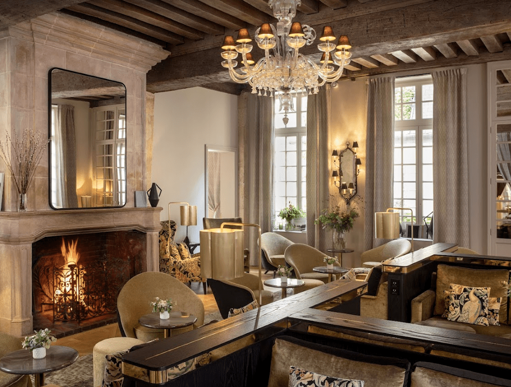 A crystal chandelier hanging over a marble fireplace.