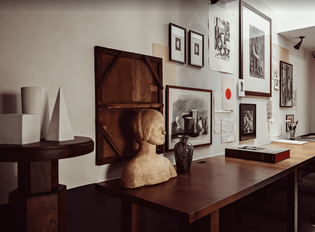 Wooden table with white sculptures and drawings.