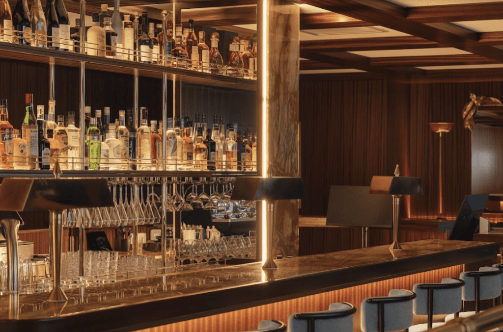 Wooden bar table with illuminated shelf of bottles.