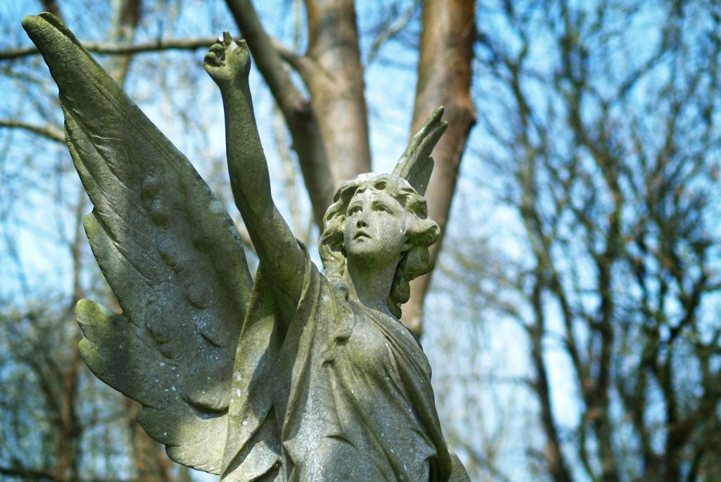 A stone angel with its arm raised to the sky.