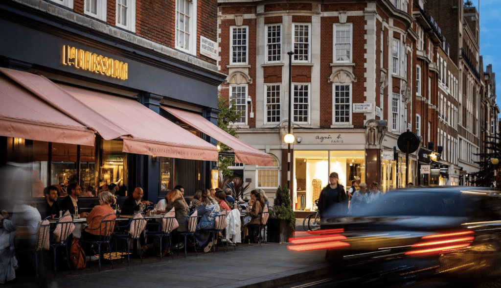 People eating at tables outside of a cafe.