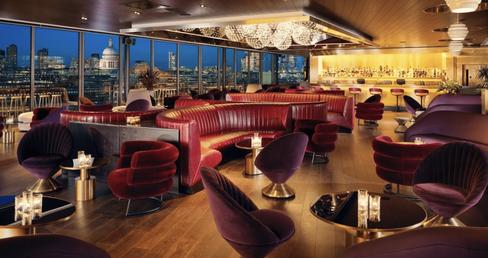 Red leather booths with purple velvet chairs and gold lighting.