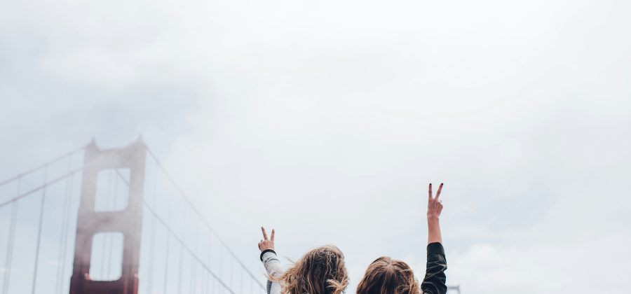 Two women traveling together standing in front of a bridge