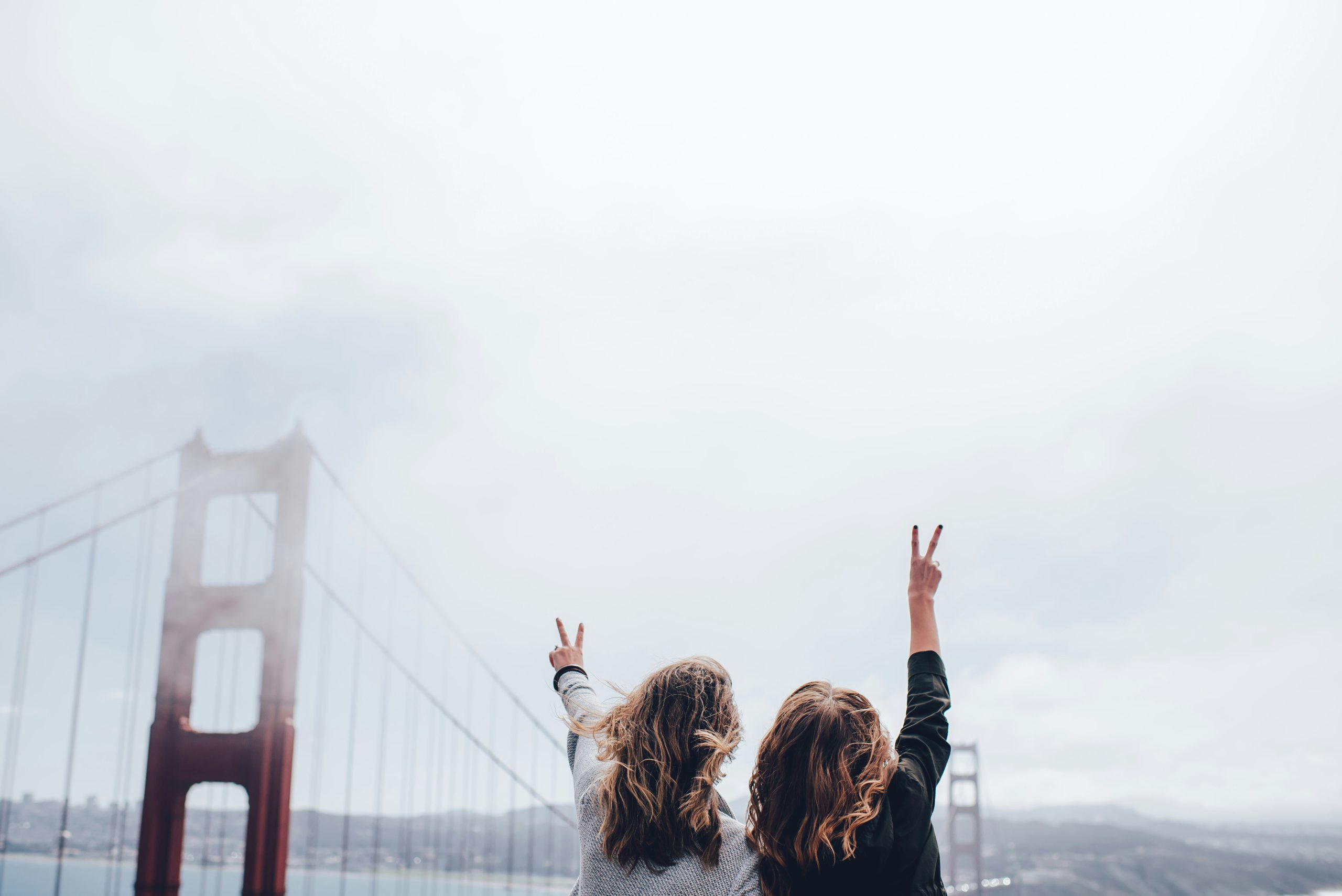 Two women traveling together standing in front of a bridge