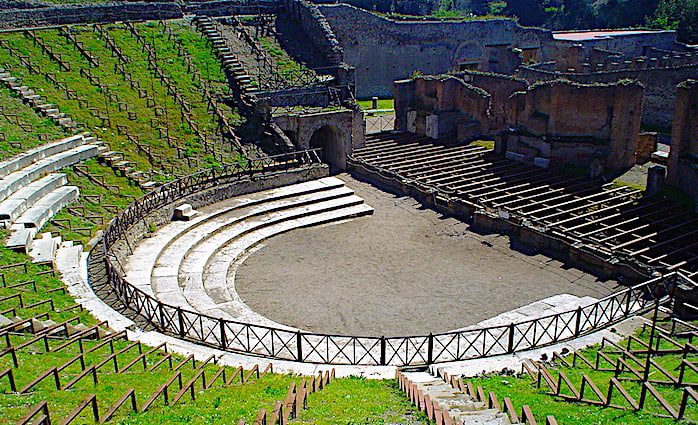 The large main amphitheater in the Pompeii Archaeological Park, semi-circular in shape with the remains of a stage.